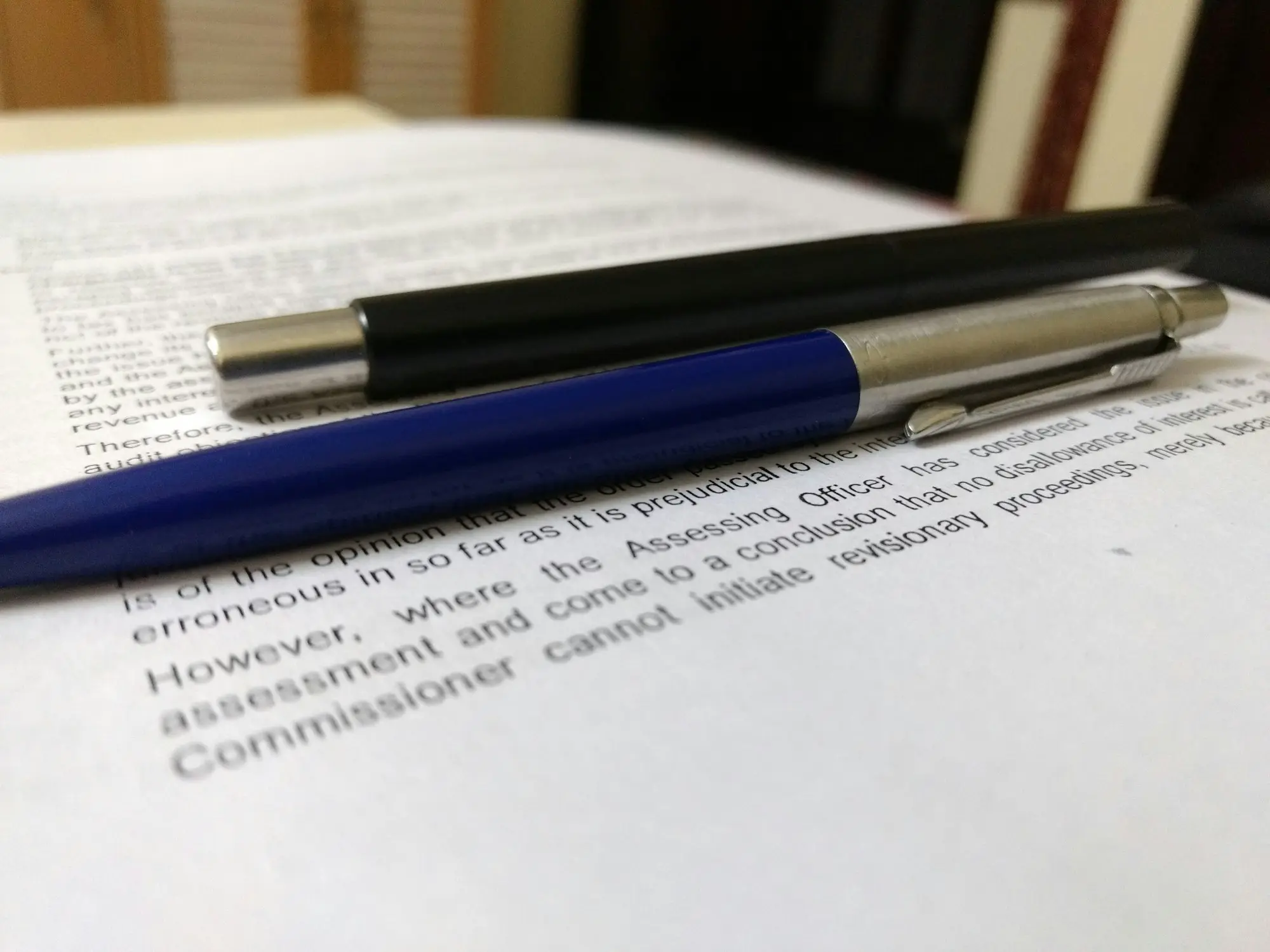Business owner comparing two printed loan offers side by side at a kitchen table